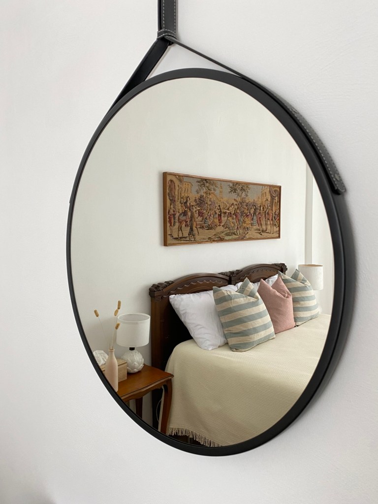 Rounded Mirror reflecting a thoughtfully designed bedroom at Casa Dolci Rodolfo with wooden bed and neutral textiles.